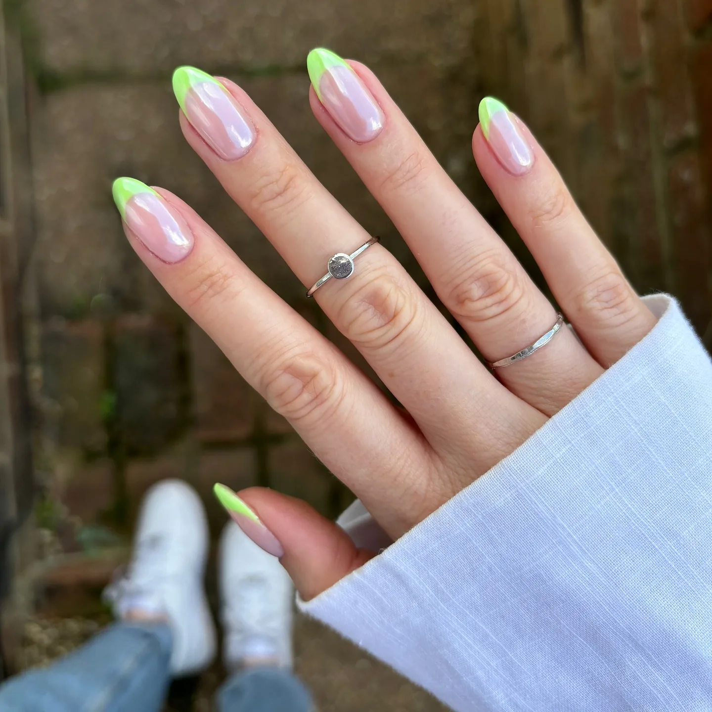 Almond nails with lime-green French tips over a glazed, pearly chrome base