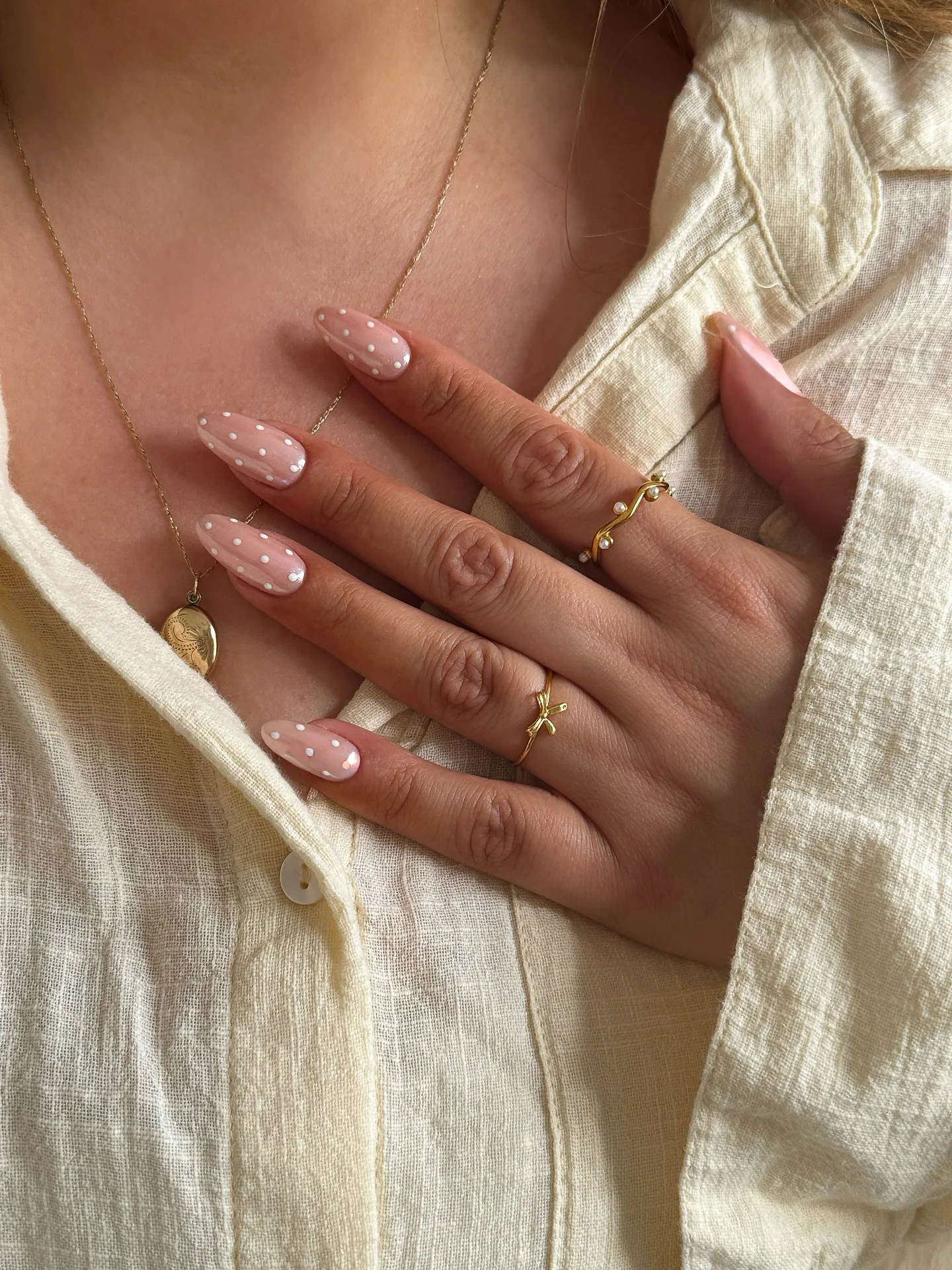 Almond nails in a sheer pink base scattered with evenly spaced white micro polka dots
