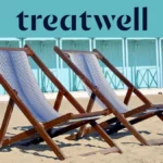 Two striped wooden deckchairs on the sand in front of pastel-blue beach huts on the Versilia coast