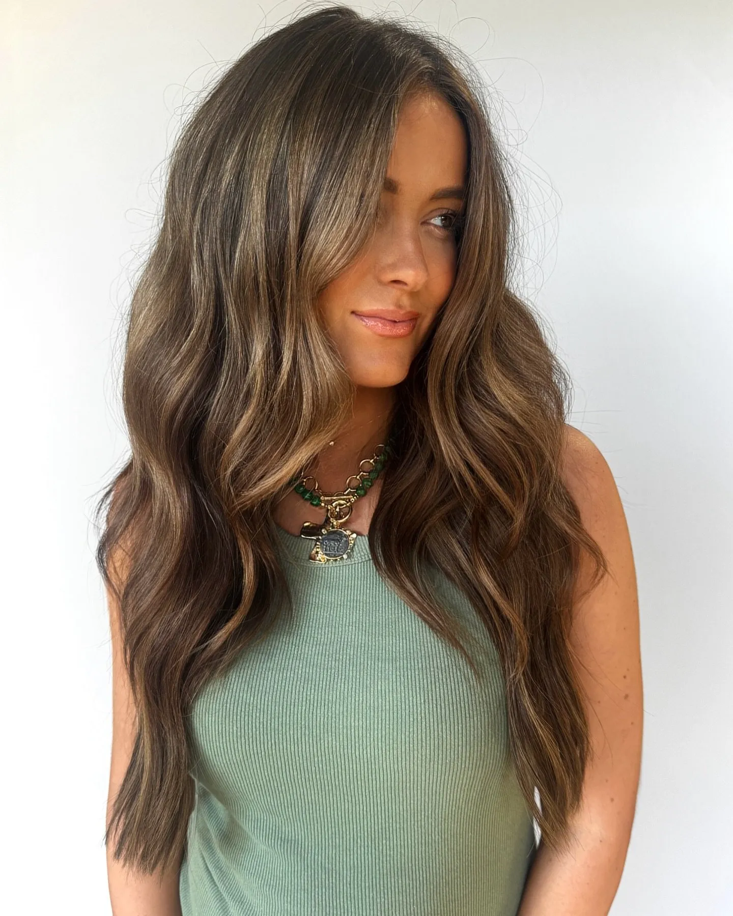 Long wavy brunette hair with soft sun-kissed French highlights concentrated through the mid-lengths and ends