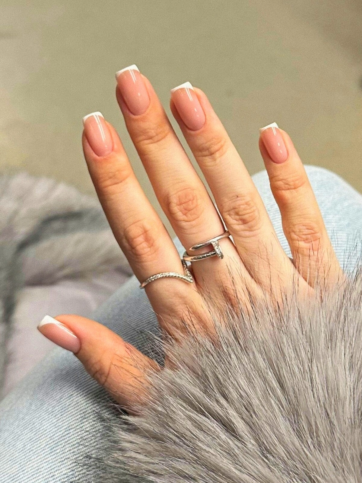 A woman’s hand showing a French tips manicure with micro lines on square nails
