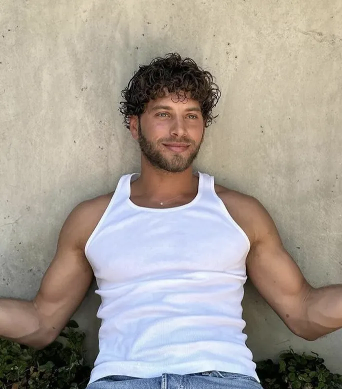 Curly mop haircut with natural voluminous texture on dark brown hair, relaxed summer portrait