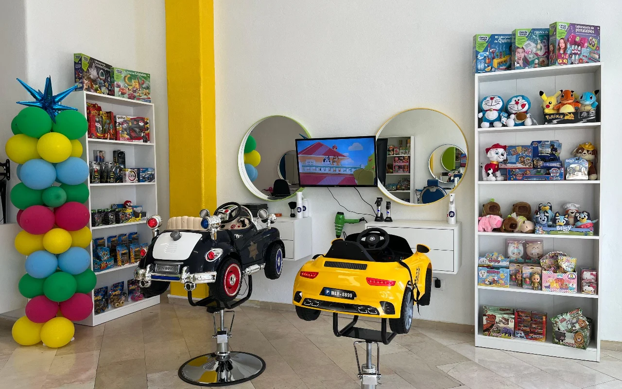 The children's area at Peluplay in Benalmádena, where the styling chairs are shaped like toy cars, with cartoon-filled shelves, round mirrors and a balloon column.