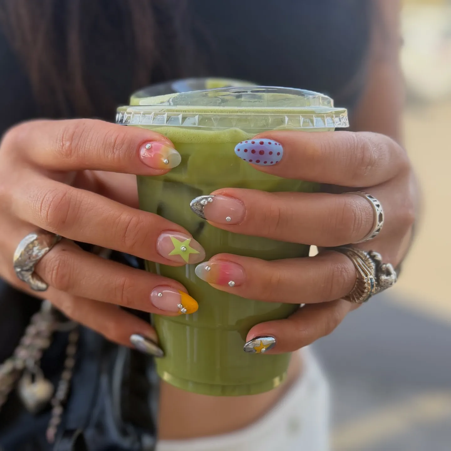 Mixed nail art set with small crystal piercings, star motifs, and colourful accents on almond-shaped nails